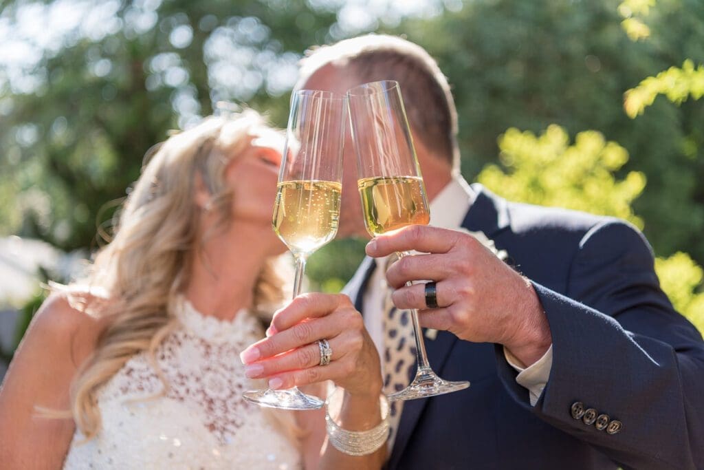 Planning private home wedding - bride & groom share kiss behind champagne flutes